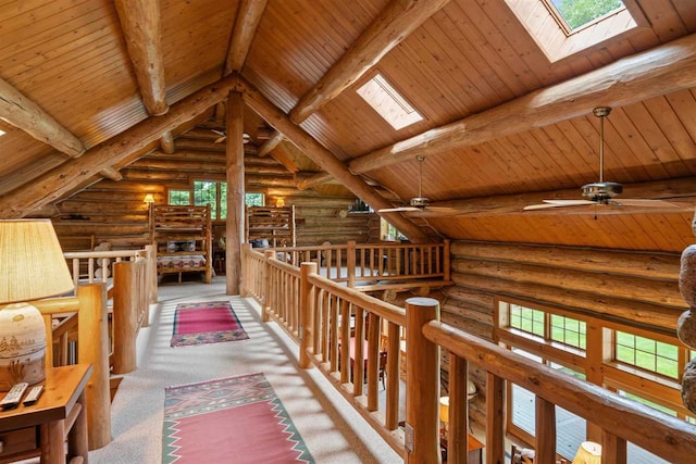 hall with beamed ceiling, a skylight, log walls, and wooden ceiling