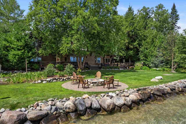 view of yard with a fire pit, a patio area, and a deck with water view