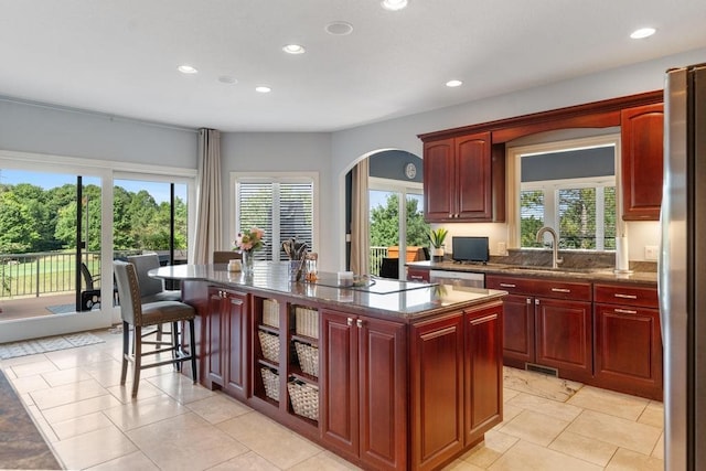 kitchen with stainless steel appliances, a kitchen island with sink, sink, and a healthy amount of sunlight