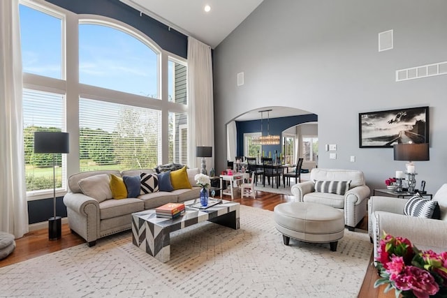 living room with hardwood / wood-style floors, high vaulted ceiling, and a chandelier