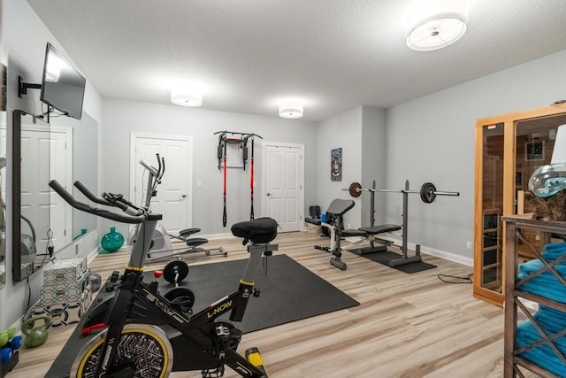 workout room with light hardwood / wood-style flooring and a textured ceiling