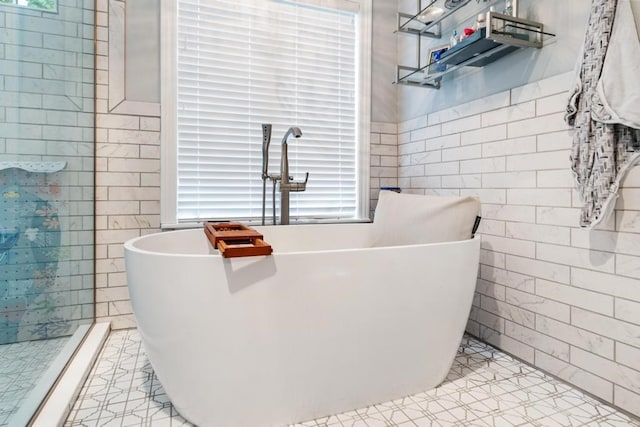 bathroom with tile patterned flooring, a tub to relax in, and tile walls