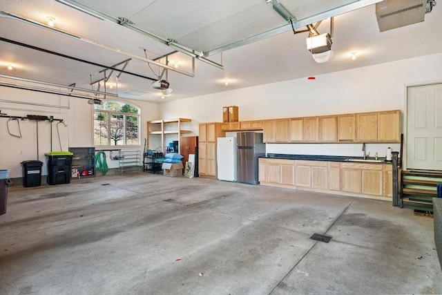 garage with stainless steel fridge, sink, white fridge, and a garage door opener