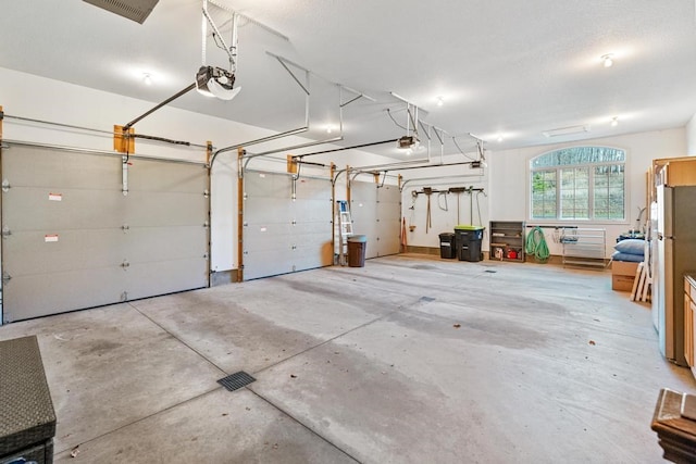 garage featuring stainless steel fridge and a garage door opener