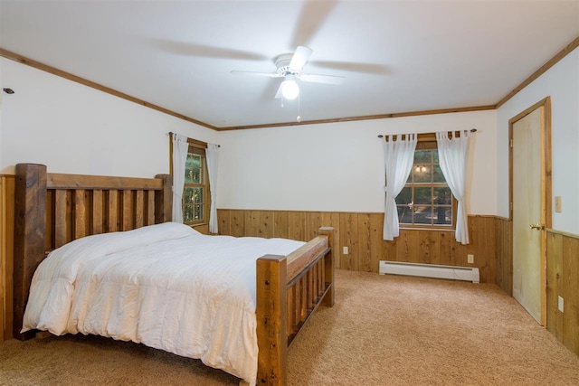 carpeted bedroom featuring crown molding, baseboard heating, ceiling fan, and wooden walls