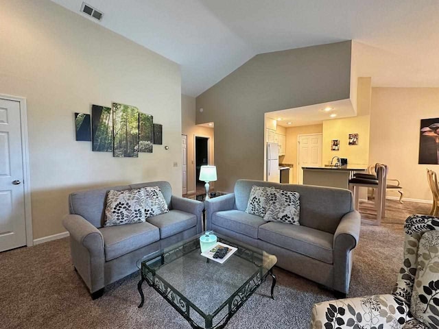 carpeted living room with high vaulted ceiling