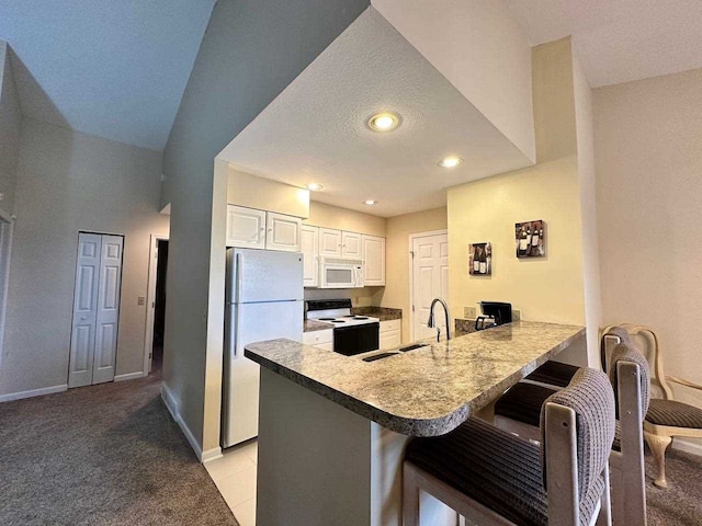 kitchen featuring white appliances, light carpet, white cabinetry, kitchen peninsula, and a breakfast bar