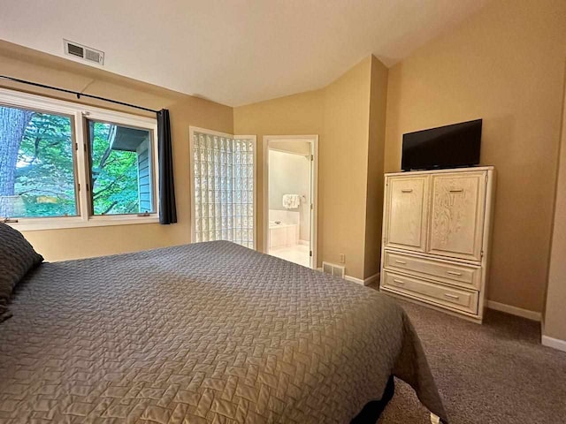 bedroom with ensuite bath, vaulted ceiling, and carpet flooring