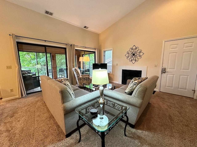 living room with carpet flooring, high vaulted ceiling, and a tile fireplace