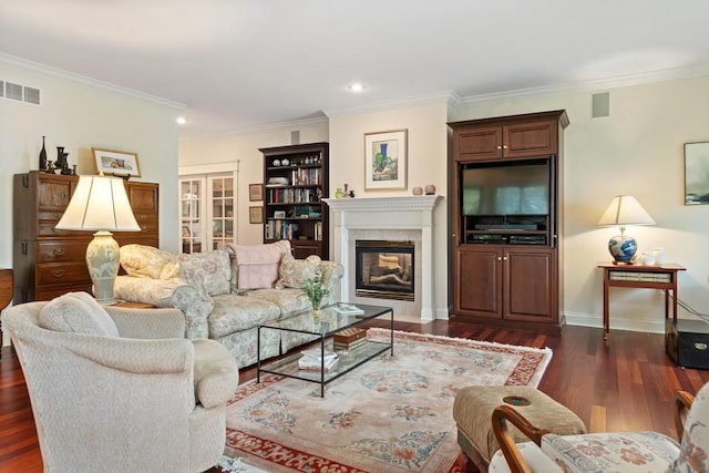 living area with dark wood-style floors, baseboards, visible vents, ornamental molding, and a glass covered fireplace