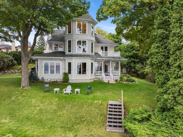 rear view of property with a balcony and a lawn