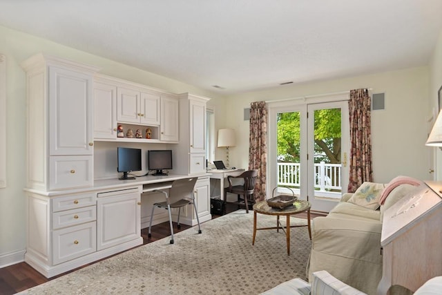 living area featuring dark wood-style floors, built in desk, and baseboards