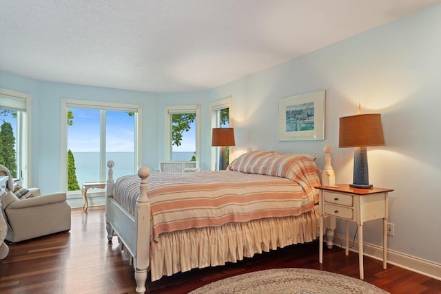 bedroom featuring access to outside, wood finished floors, baseboards, and a textured ceiling