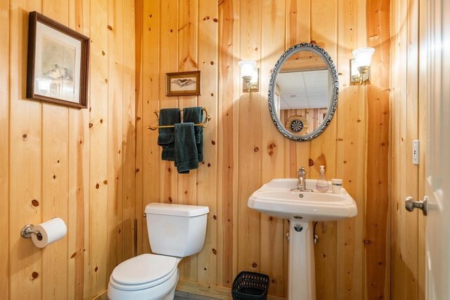 bathroom featuring wooden walls and toilet