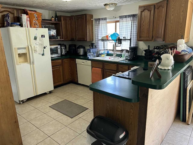 kitchen with a textured ceiling, sink, white appliances, and light tile patterned flooring