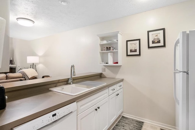 kitchen featuring a textured ceiling, sink, white appliances, and white cabinetry