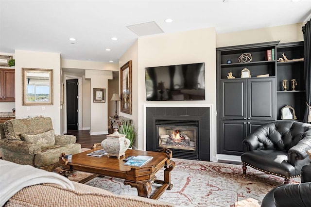 living room with a tiled fireplace and hardwood / wood-style floors