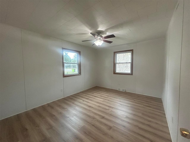 unfurnished room featuring wood-type flooring, ceiling fan, and plenty of natural light