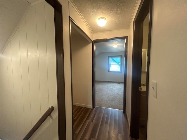 corridor with ornamental molding, lofted ceiling, a textured ceiling, and dark hardwood / wood-style floors