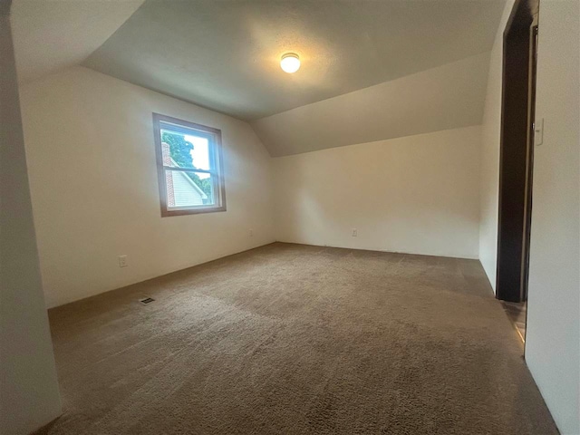 additional living space featuring vaulted ceiling and dark carpet