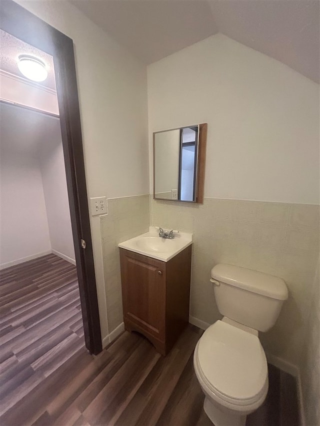 bathroom with lofted ceiling, vanity, toilet, and hardwood / wood-style flooring