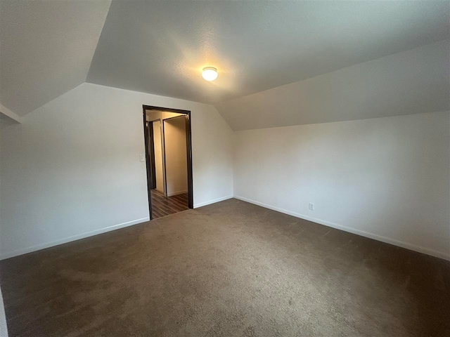 additional living space with lofted ceiling and dark colored carpet