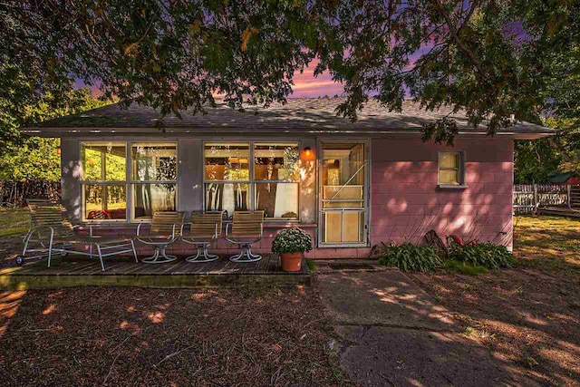 back house at dusk featuring a patio