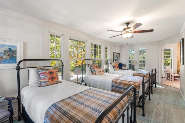 bedroom with ceiling fan, light wood-type flooring, crown molding, and multiple windows