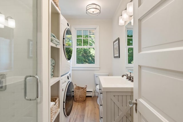 bathroom featuring stacked washer / drying machine, an enclosed shower, hardwood / wood-style floors, vanity, and toilet