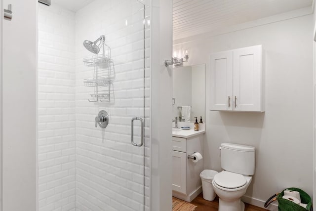 bathroom featuring vanity, hardwood / wood-style flooring, a shower with shower door, and toilet