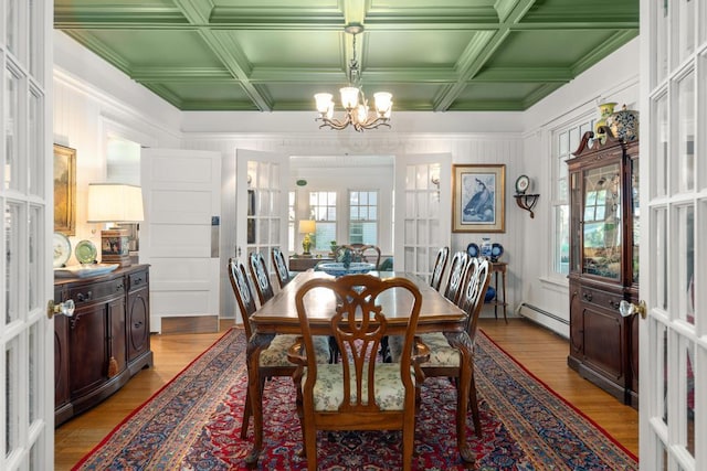 dining space featuring light hardwood / wood-style floors, coffered ceiling, french doors, a baseboard radiator, and a notable chandelier