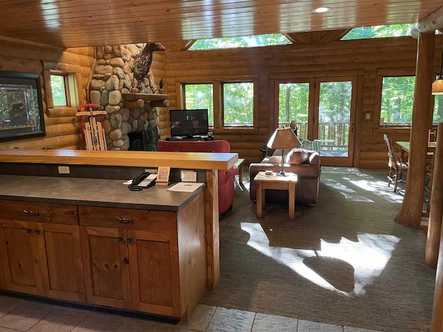 kitchen featuring wood ceiling, log walls, carpet flooring, and a stone fireplace