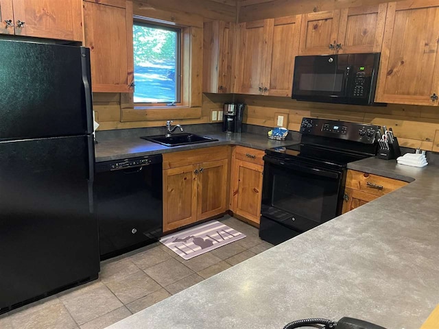 kitchen with light tile patterned floors, wood walls, sink, and black appliances