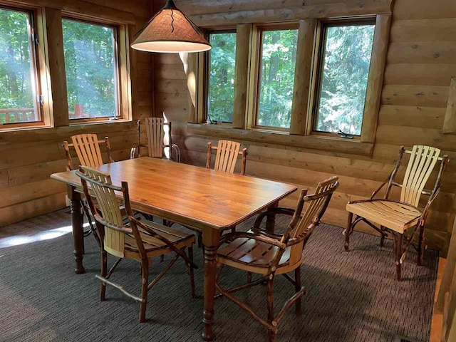 carpeted dining space featuring wooden walls and a wealth of natural light