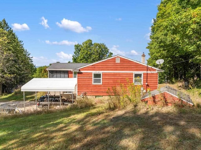 back of property with a yard, a carport, and a sunroom