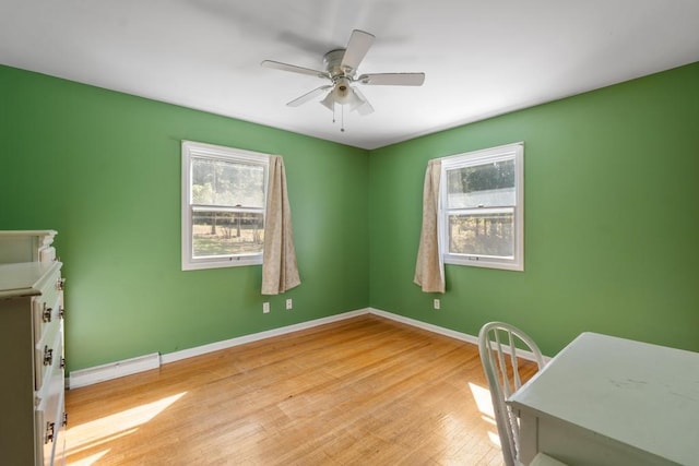 bedroom with ceiling fan, a baseboard radiator, light hardwood / wood-style floors, and multiple windows