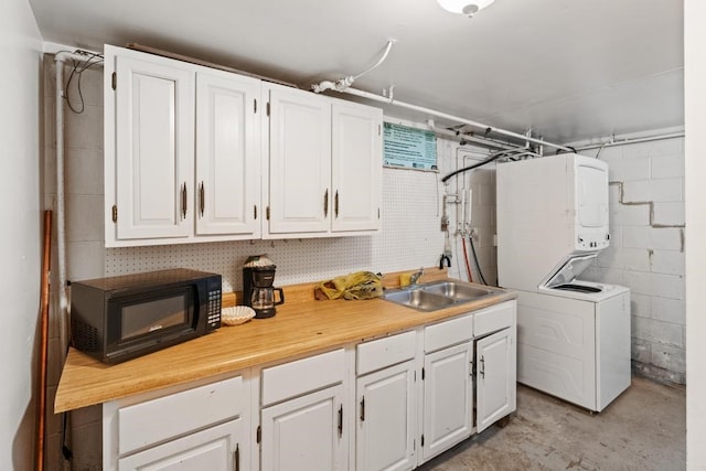 washroom with stacked washing maching and dryer and sink