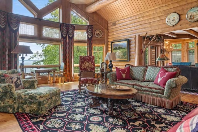 living area featuring rustic walls, a wealth of natural light, wood finished floors, and high vaulted ceiling