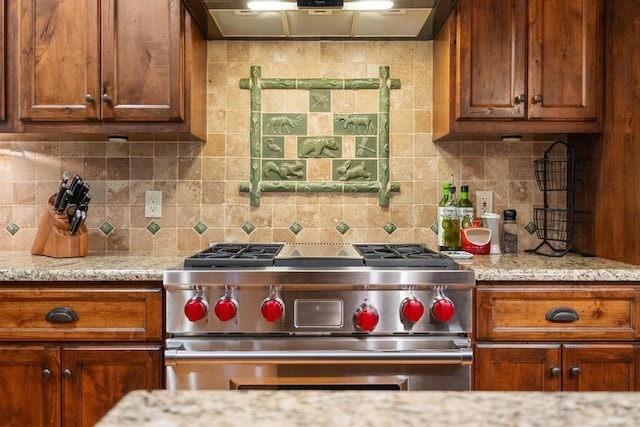 kitchen featuring light stone counters, decorative backsplash, luxury range, and wall chimney exhaust hood