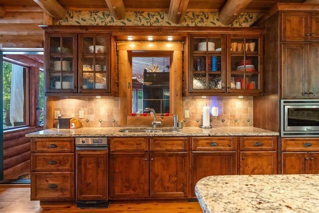 bar featuring light wood-type flooring, a sink, stainless steel microwave, and beamed ceiling