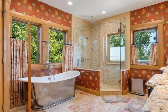 bathroom featuring a freestanding bath, a stall shower, and wallpapered walls