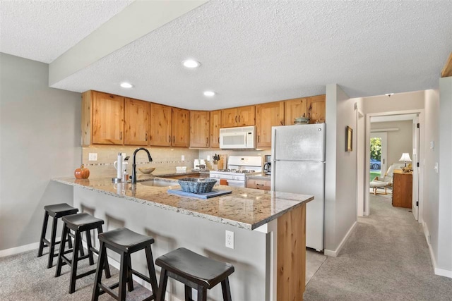 kitchen featuring light colored carpet, kitchen peninsula, sink, and white appliances