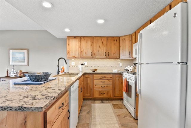 kitchen featuring light stone counters, a textured ceiling, sink, and white appliances