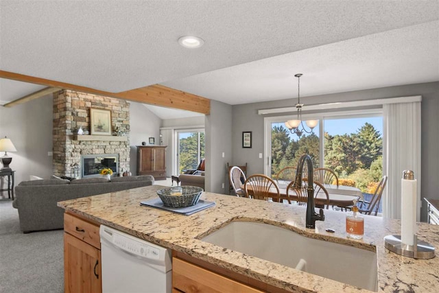 kitchen featuring a fireplace, dishwasher, decorative light fixtures, sink, and light colored carpet