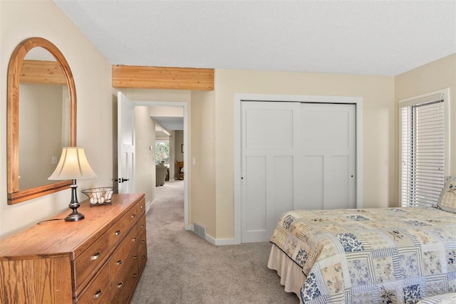 bedroom featuring a textured ceiling, light colored carpet, and a closet