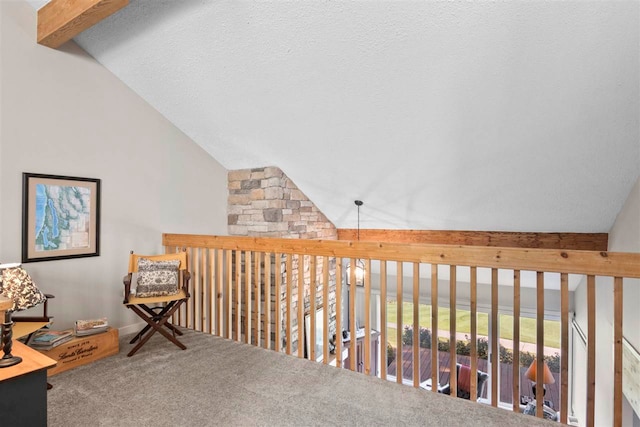 hallway with carpet floors, vaulted ceiling with beams, and a textured ceiling