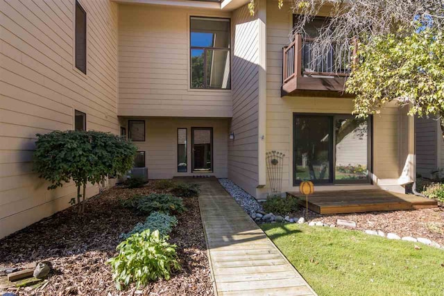 doorway to property featuring a balcony and a yard