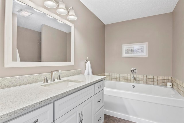 bathroom featuring a tub to relax in, a textured ceiling, and vanity