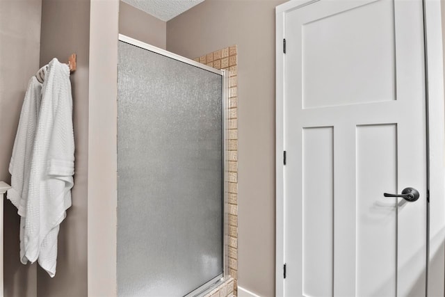 bathroom with a textured ceiling and an enclosed shower