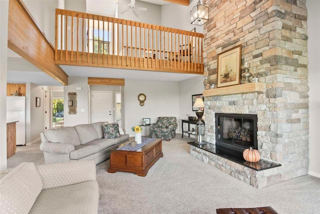 living room featuring light carpet, a towering ceiling, ceiling fan, and a fireplace